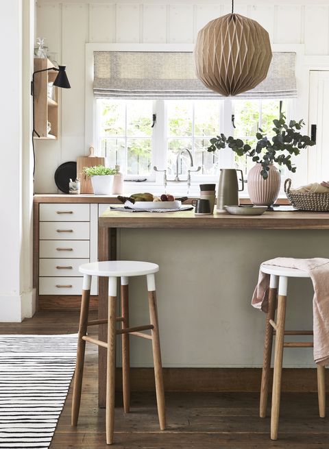 lagom, švedska ideja, da ima ravno pravo količino, je ujeta v popolno ravnovesje nevtralnih odtenkov rožnate barve, lesa in prijetnih tekstur, nevtralne in lesene kuhinje s kuhinjskim pultom, belimi pobarvanimi blatniki in predalniki, ki dodajo ravno dovolj kontrasta tej elegantni leseni viseči svetilki