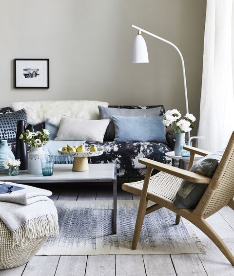 dnevna soba z blazinami na kavču z modrim vzorcem, bela talna svetilka, upognjena nad sedežno garnituro, kapljice in vzorci krožnikov za sodoben in sproščen videz