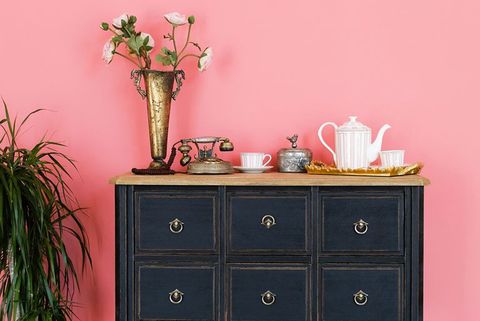 comoda veche cu obiecte pe fundalul unui perete roz urmează o floare într-un ghiveci interior frumos în stil vintage
